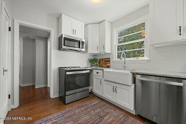 kitchen with white cabinets, sink, light stone countertops, appliances with stainless steel finishes, and dark hardwood / wood-style flooring