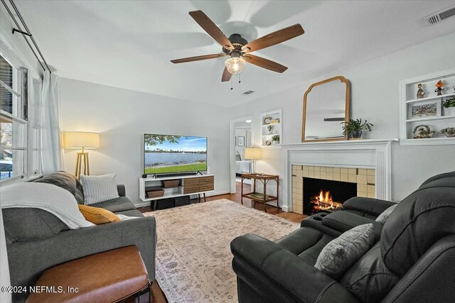 living room with a fireplace, wood-type flooring, built in features, and ceiling fan