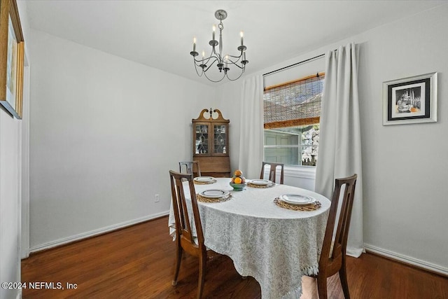 dining space featuring dark wood-type flooring and an inviting chandelier