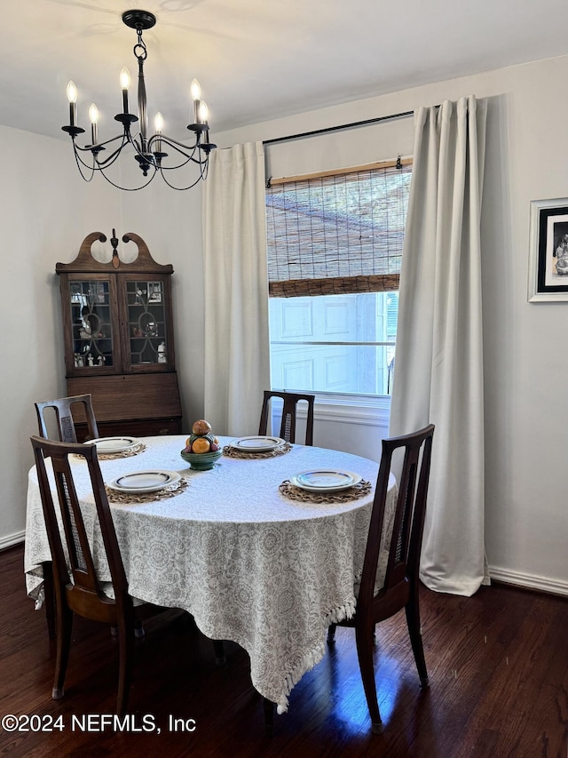 dining space featuring dark wood-type flooring, a healthy amount of sunlight, and an inviting chandelier