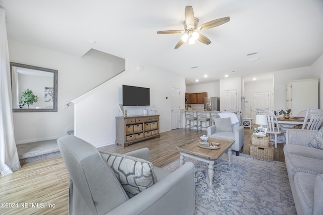 living room with light hardwood / wood-style flooring and ceiling fan