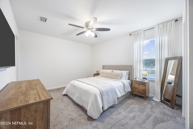 bedroom featuring a textured ceiling, ceiling fan, and light carpet