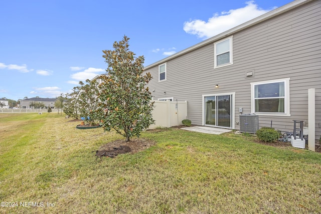 rear view of property featuring a lawn and central AC