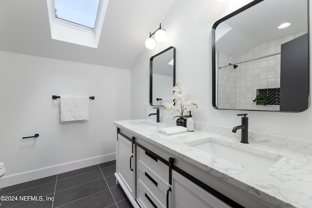 bathroom with tile patterned floors, lofted ceiling with skylight, and vanity