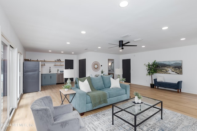 living room with light hardwood / wood-style flooring, ceiling fan, and sink