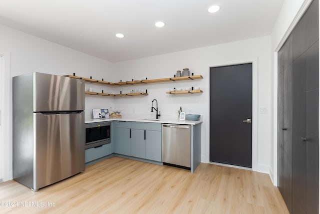 kitchen featuring gray cabinets, sink, appliances with stainless steel finishes, and light hardwood / wood-style flooring