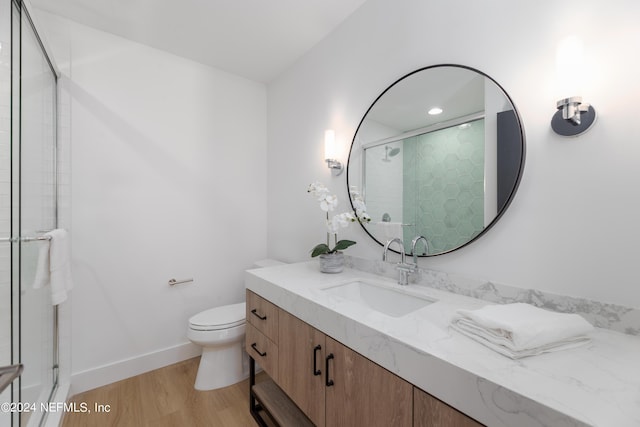 bathroom with wood-type flooring, vanity, toilet, and an enclosed shower