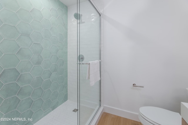 bathroom with hardwood / wood-style floors, toilet, and an enclosed shower