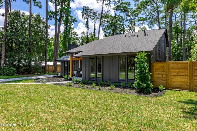 rear view of house with a sunroom and a lawn