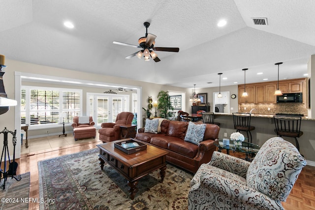 living room with ceiling fan with notable chandelier, dark parquet flooring, a textured ceiling, and vaulted ceiling