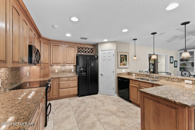 kitchen with light stone countertops, sink, black appliances, and decorative light fixtures