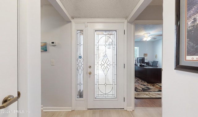 entryway with light wood-type flooring, a textured ceiling, and ceiling fan