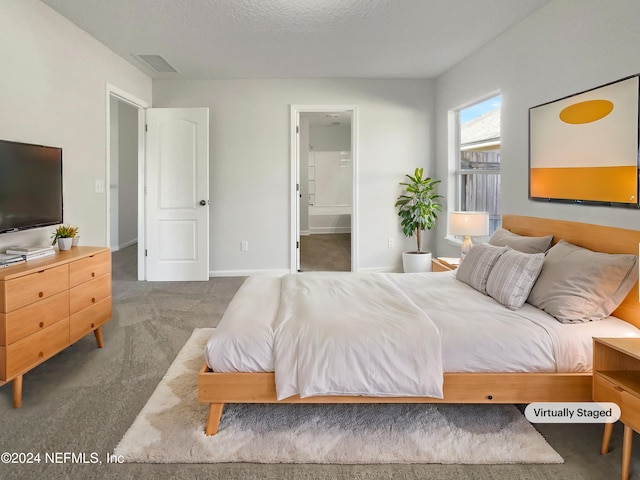 bedroom with dark colored carpet, a textured ceiling, and ensuite bathroom