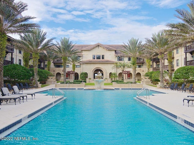 view of pool featuring pool water feature, an outdoor fireplace, and a patio