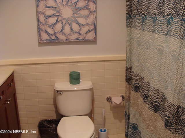 bathroom featuring vanity, toilet, and tile walls