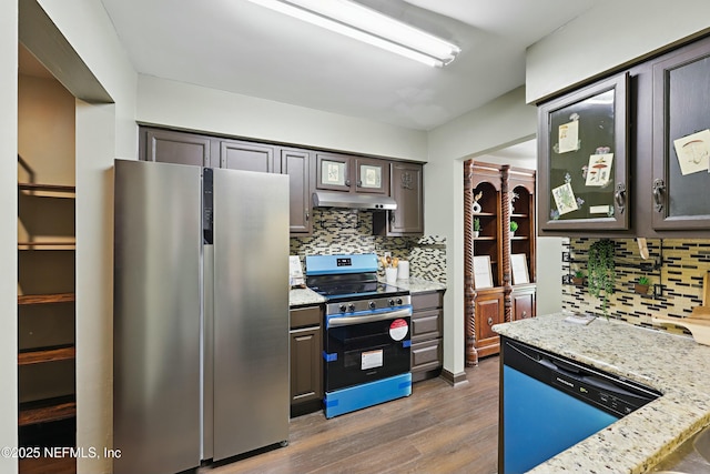 11657 Tanager Dr, Jacksonville, FL 32225 - kitchen featuring light stone counters, dark wood finished floors, under cabinet range hood, appliances with stainless steel finishes, and backsplash