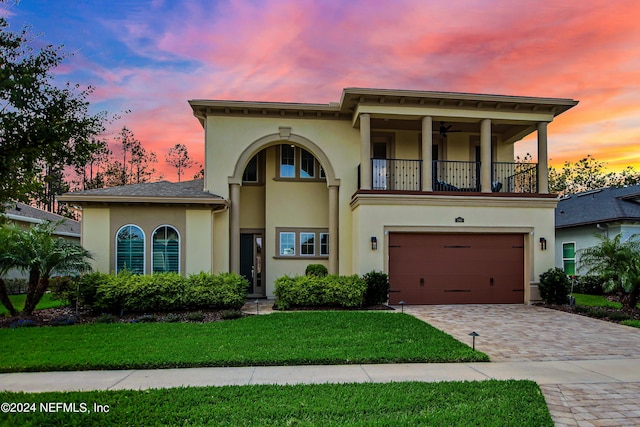 view of front of home featuring a yard, a balcony, and a garage