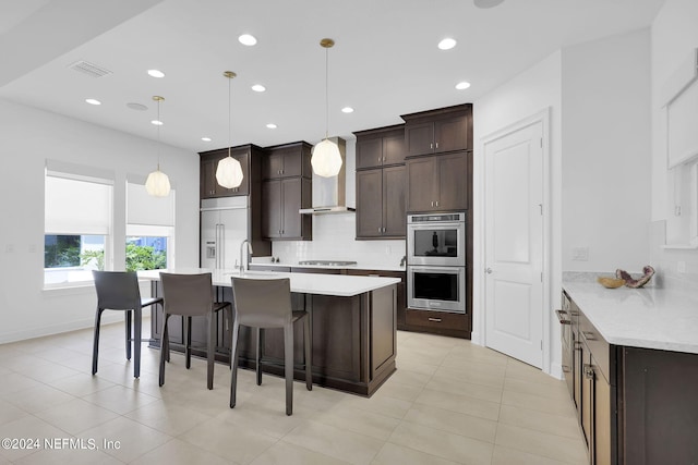 kitchen featuring decorative backsplash, a breakfast bar, dark brown cabinetry, stainless steel appliances, and hanging light fixtures