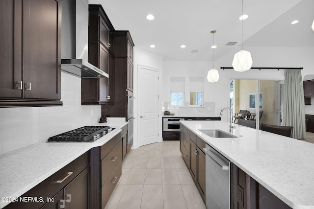 kitchen featuring sink, wall chimney exhaust hood, tasteful backsplash, pendant lighting, and appliances with stainless steel finishes