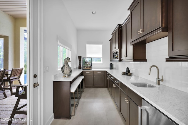 kitchen with backsplash, stainless steel dishwasher, dark brown cabinetry, and sink