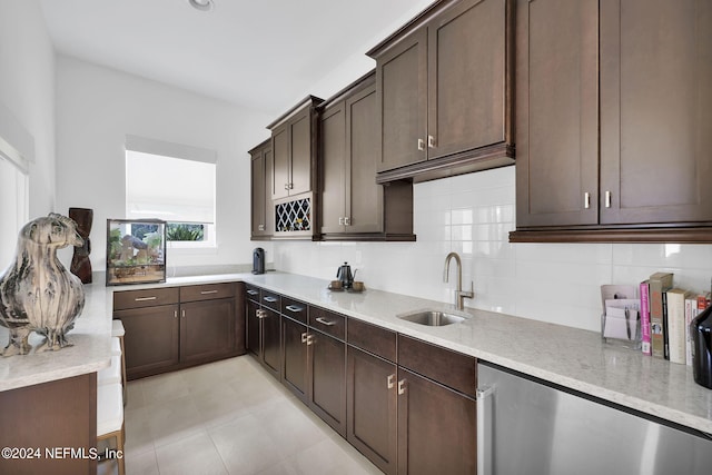 kitchen featuring dark brown cabinetry, sink, tasteful backsplash, light stone counters, and stainless steel fridge