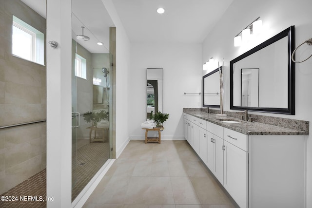 bathroom featuring tiled shower, vanity, and tile patterned flooring