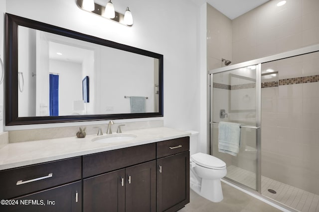 bathroom with tile patterned floors, vanity, an enclosed shower, and toilet