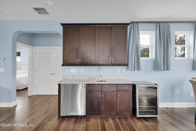 bar with dark hardwood / wood-style flooring, dark brown cabinets, beverage cooler, and stainless steel dishwasher