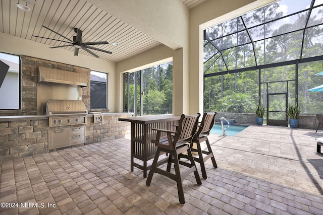 view of patio / terrace with glass enclosure, grilling area, exterior kitchen, ceiling fan, and a bar