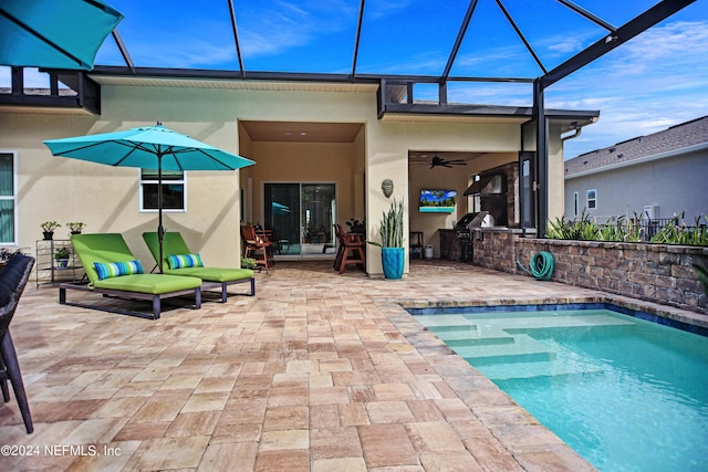 view of pool featuring a lanai, ceiling fan, a patio area, and exterior kitchen