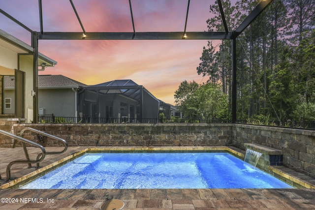 pool at dusk with pool water feature and a lanai