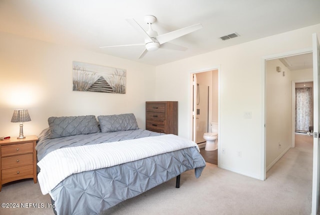 bedroom featuring ceiling fan, light colored carpet, and connected bathroom