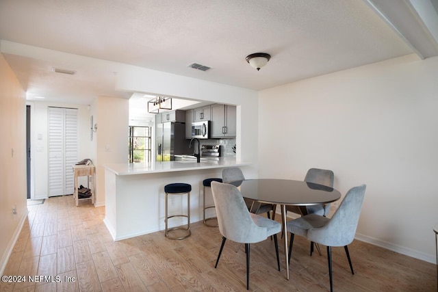 dining area with light hardwood / wood-style flooring, a notable chandelier, and sink