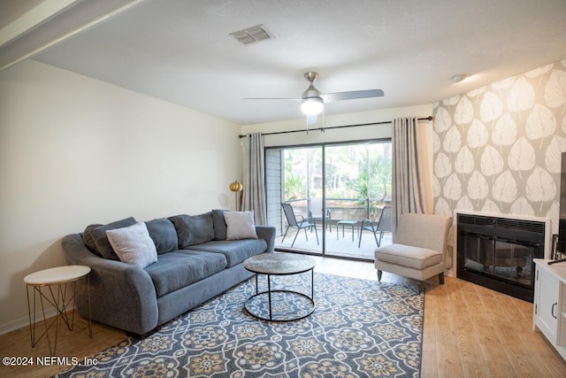 living room featuring ceiling fan, a fireplace, and light hardwood / wood-style flooring