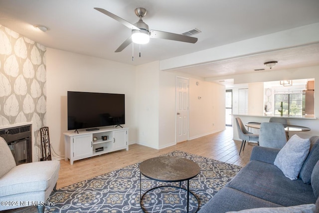 living room featuring ceiling fan, a fireplace, and light hardwood / wood-style flooring