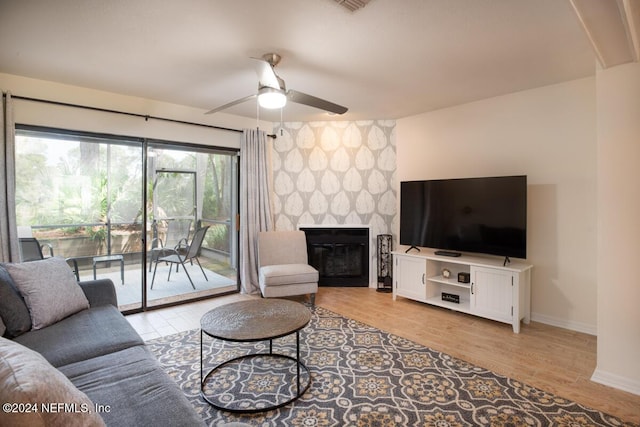 living room with ceiling fan, a fireplace, and light wood-type flooring