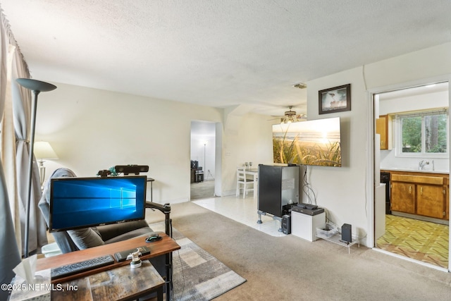 living room with a textured ceiling, ceiling fan, and sink