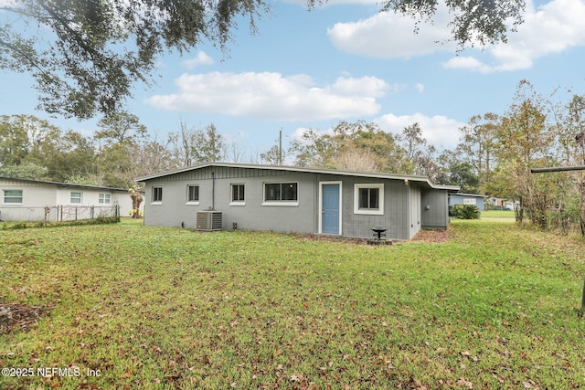 rear view of house with central air condition unit and a yard