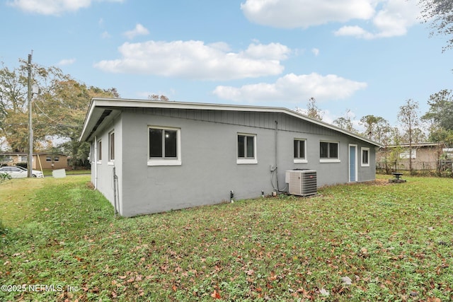 rear view of house with a lawn and cooling unit