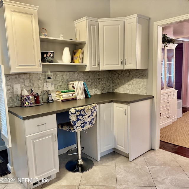 kitchen featuring light tile patterned floors, built in desk, and white cabinetry