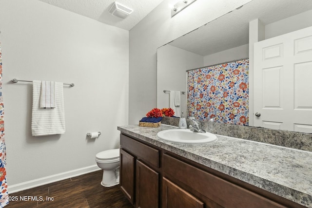 bathroom featuring vanity, wood-type flooring, toilet, and a textured ceiling