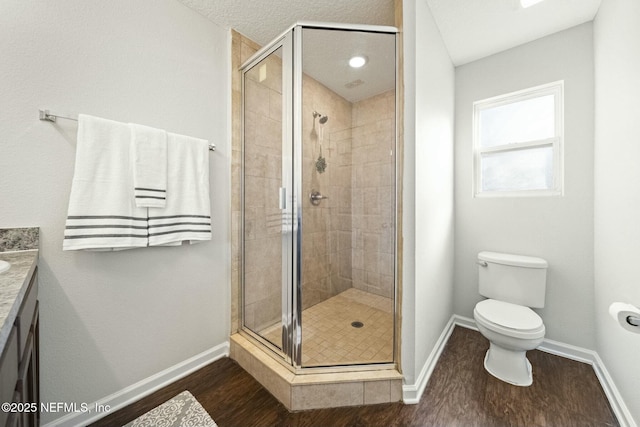 bathroom featuring wood-type flooring, vanity, toilet, a shower with door, and a textured ceiling