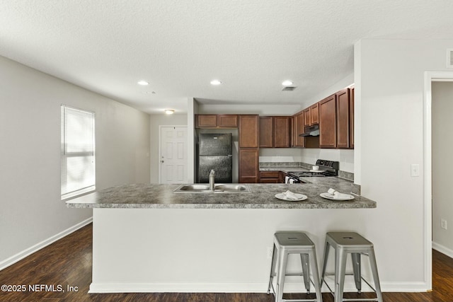 kitchen featuring sink, dark wood-type flooring, black appliances, a textured ceiling, and kitchen peninsula