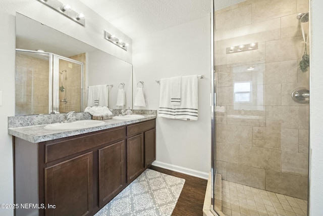 bathroom with hardwood / wood-style flooring, vanity, a textured ceiling, and a shower with shower door