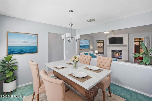 dining area with an inviting chandelier, carpet, and a brick fireplace