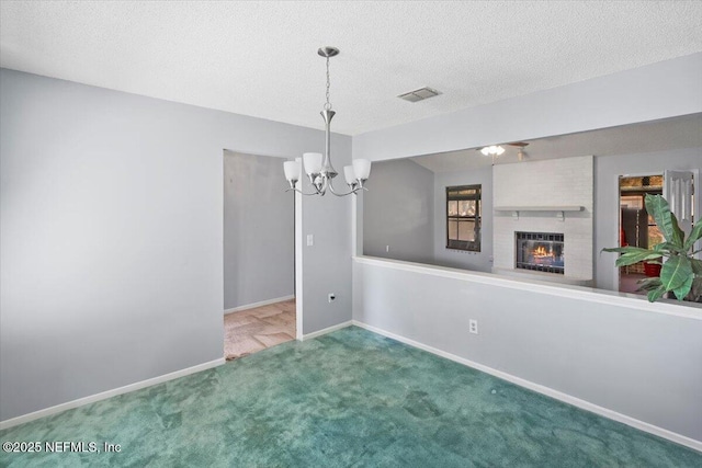 unfurnished dining area with carpet flooring, a textured ceiling, a brick fireplace, and an inviting chandelier