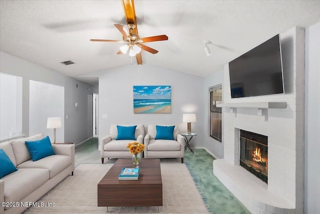 carpeted living room with vaulted ceiling with beams, ceiling fan, and a brick fireplace