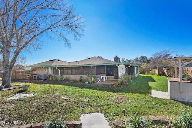 back of property featuring a sunroom, a yard, and central AC