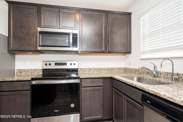 kitchen featuring light stone countertops, sink, stainless steel appliances, and dark brown cabinets