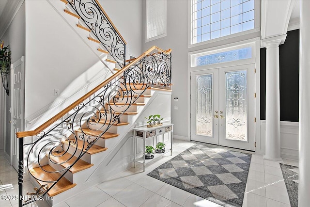 tiled entrance foyer featuring ornate columns, french doors, and a towering ceiling